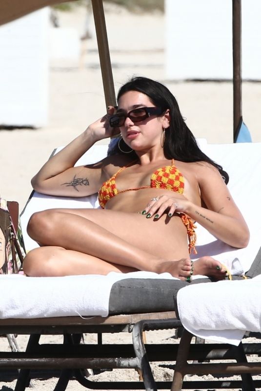 DUA LIPA in Bikini Lounges at a Beach in Miami 02/10/2022