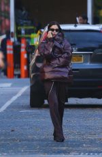 IRINA SHAYK in a Plum-colored Puffer Coat, Dark Brown Pants and Sleek Black Boots Out in New York 10/28/2024