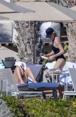 CHARLIZE THERON in a Black Swimsuit at a Pool in Cabo 12/30/2024