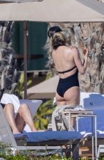 CHARLIZE THERON in a Black Swimsuit at a Pool in Cabo 12/30/2024