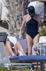 CHARLIZE THERON in a Black Swimsuit at a Pool in Cabo 12/30/2024