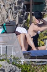 CHARLIZE THERON in a Black Swimsuit at a Pool in Cabo 12/30/2024