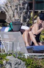 CHARLIZE THERON in a Black Swimsuit at a Pool in Cabo 12/30/2024
