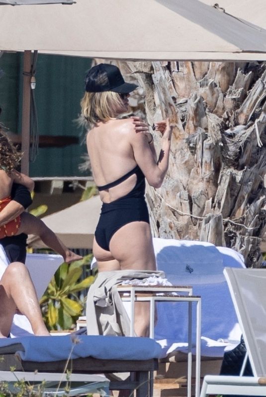 CHARLIZE THERON in a Black Swimsuit at a Pool in Cabo 12/30/2024